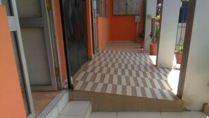 Un pasillo con piso a cuadros, una reja metálica y una planta en maceta.