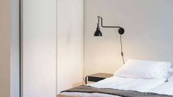 Ein Schlafzimmer mit einem Bett, einem Nachttisch, einer Lampe und einem Kleiderschrank.