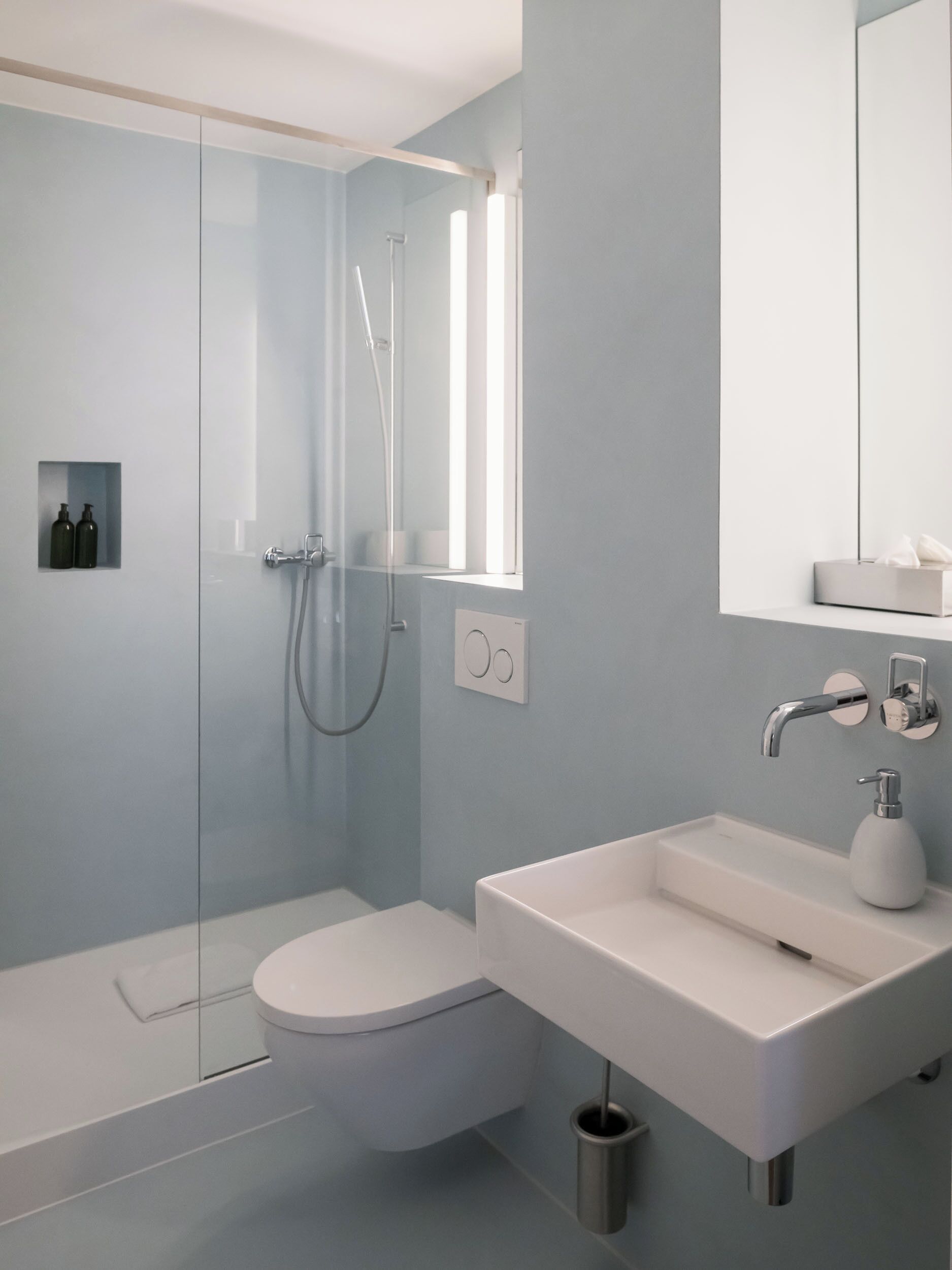 Une salle de bain moderne avec une douche à parois de verre, des toilettes blanches et un lavabo avec un miroir au-dessus.