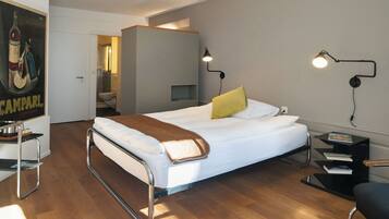 Una habitación de hotel moderna con una cama, mesitas de noche, un escritorio y un baño visible a través de una puerta abierta.