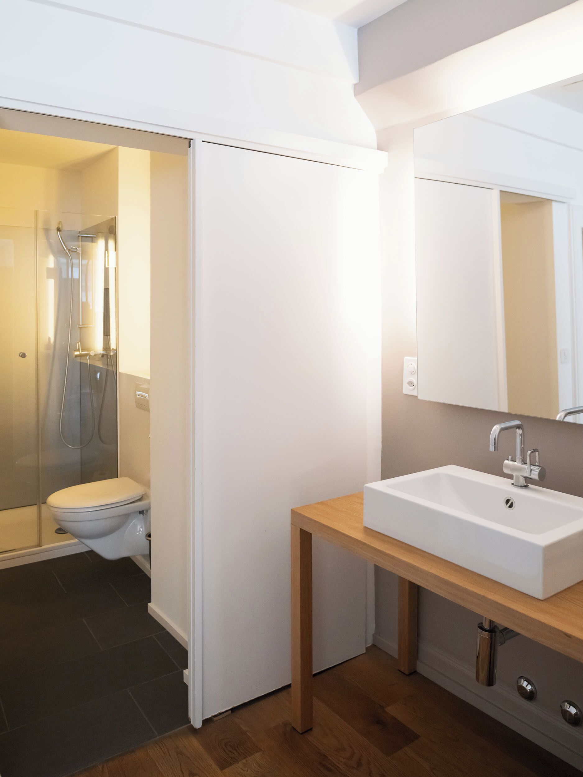 A modern bathroom with a shower, toilet, and sink.