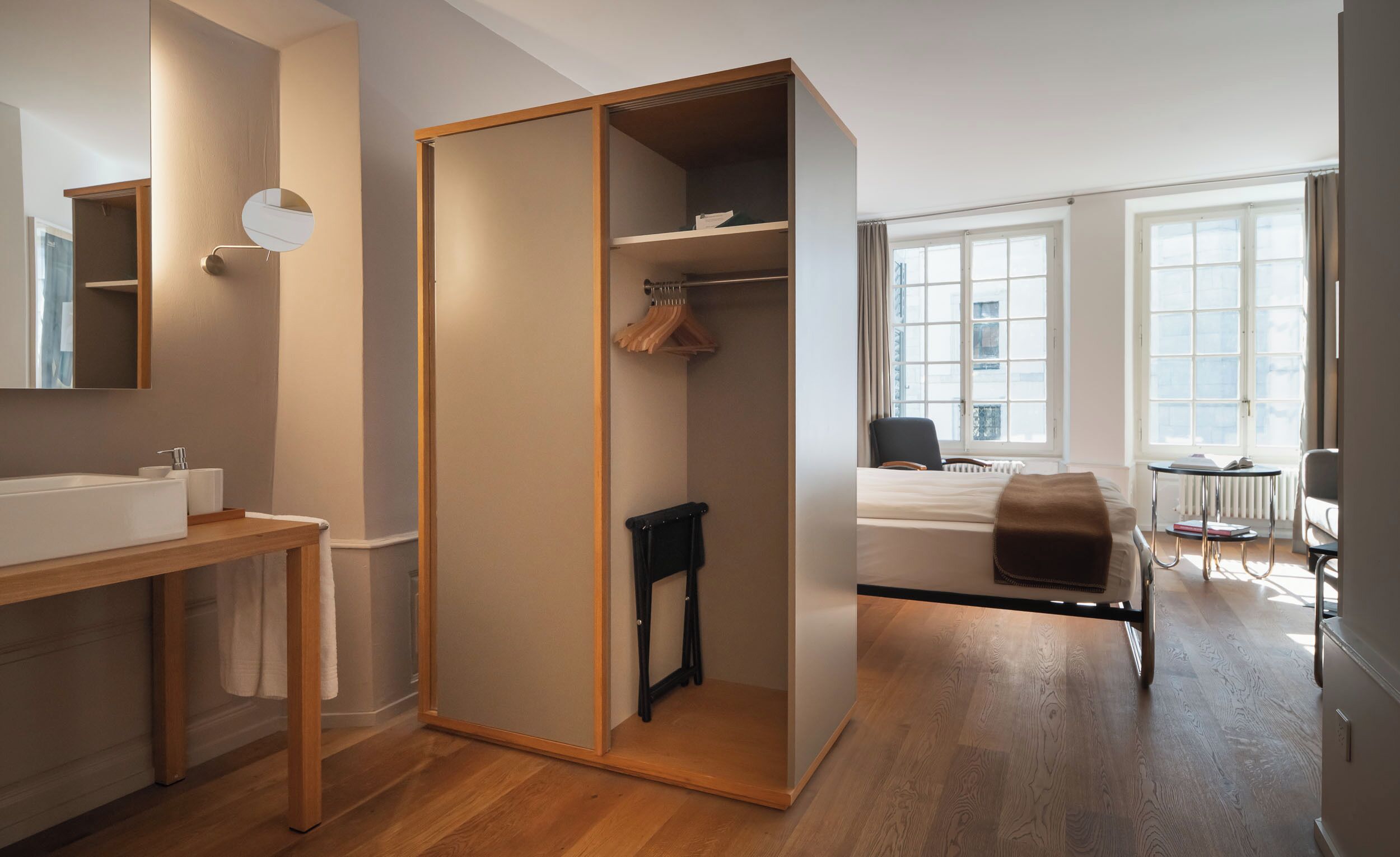 Ein modernes Badezimmer mit einem Holzkosmetikschrank, einem Spiegel und einem großen Fenster.