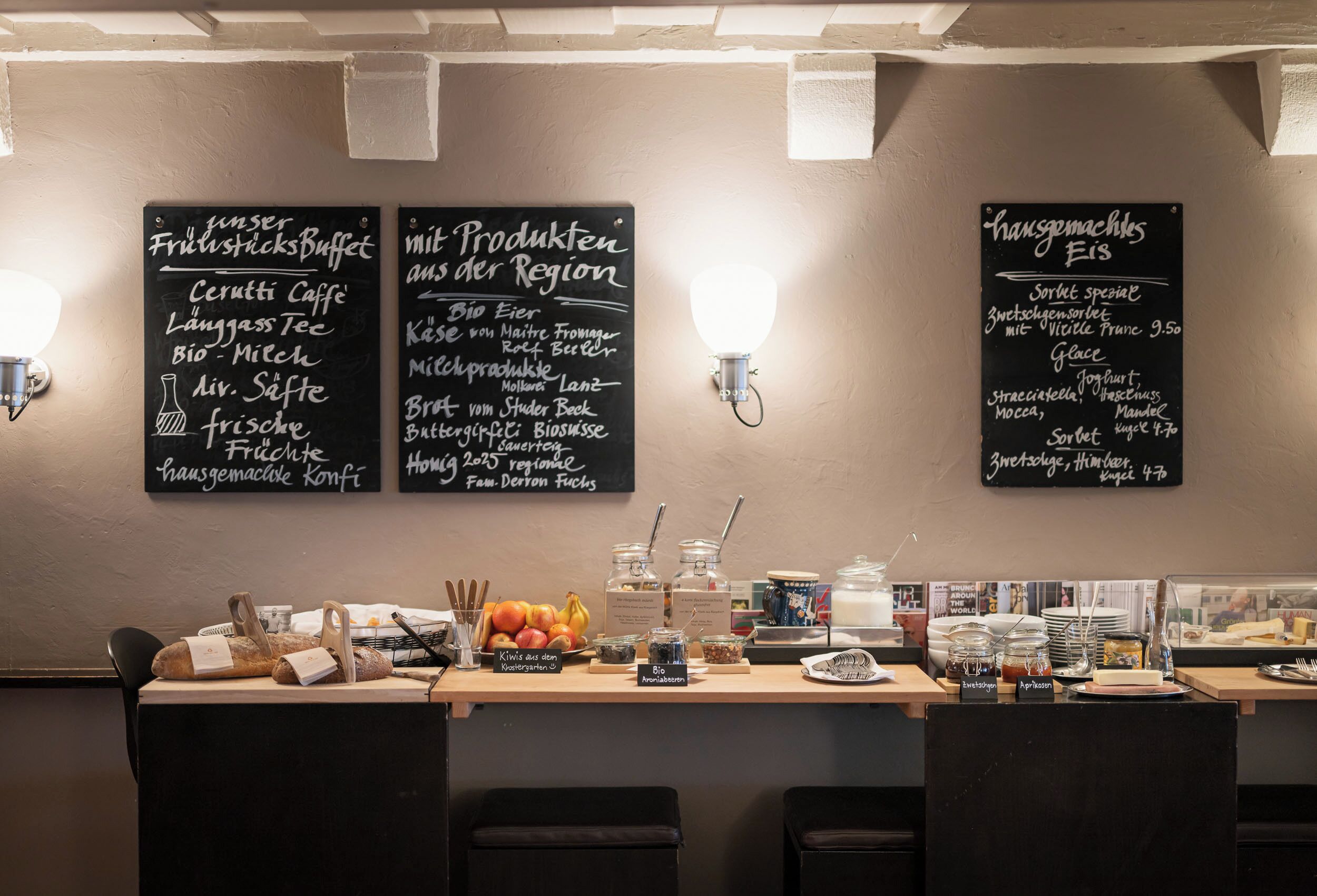A breakfast buffet area with various food items and a chalkboard menu listing regional products.