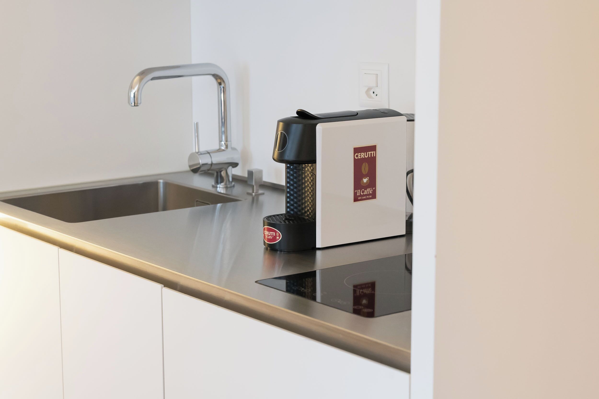 A modern kitchen with a stainless steel sink, a coffee machine, and a built-in induction cooktop.