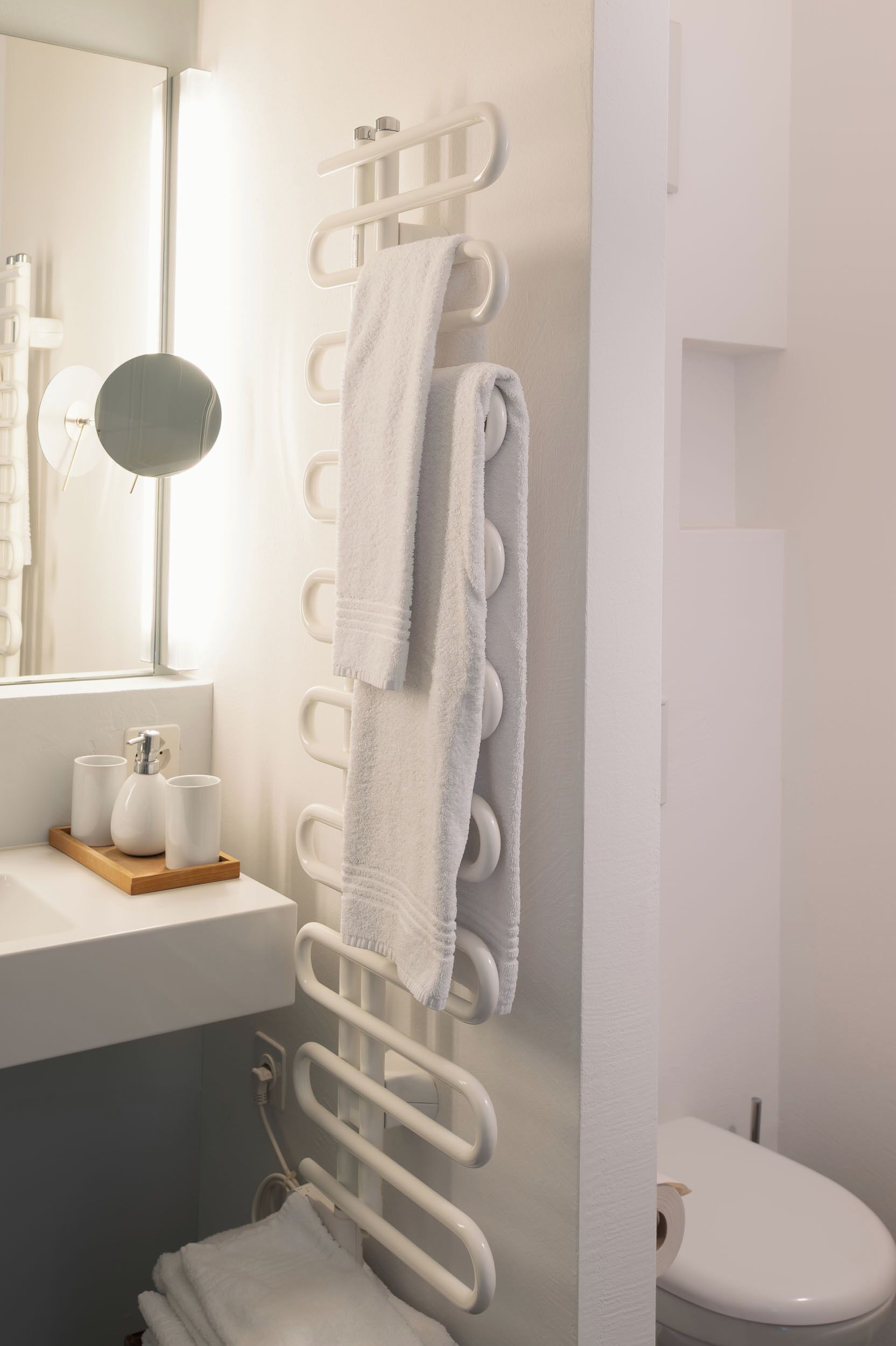A bathroom with a white sink, mirror, towel rack, and toilet.