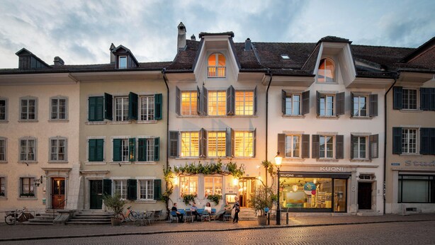 Un hotel con una facciata in stile europeo, diverse finestre e una strada acciottolata di fronte.