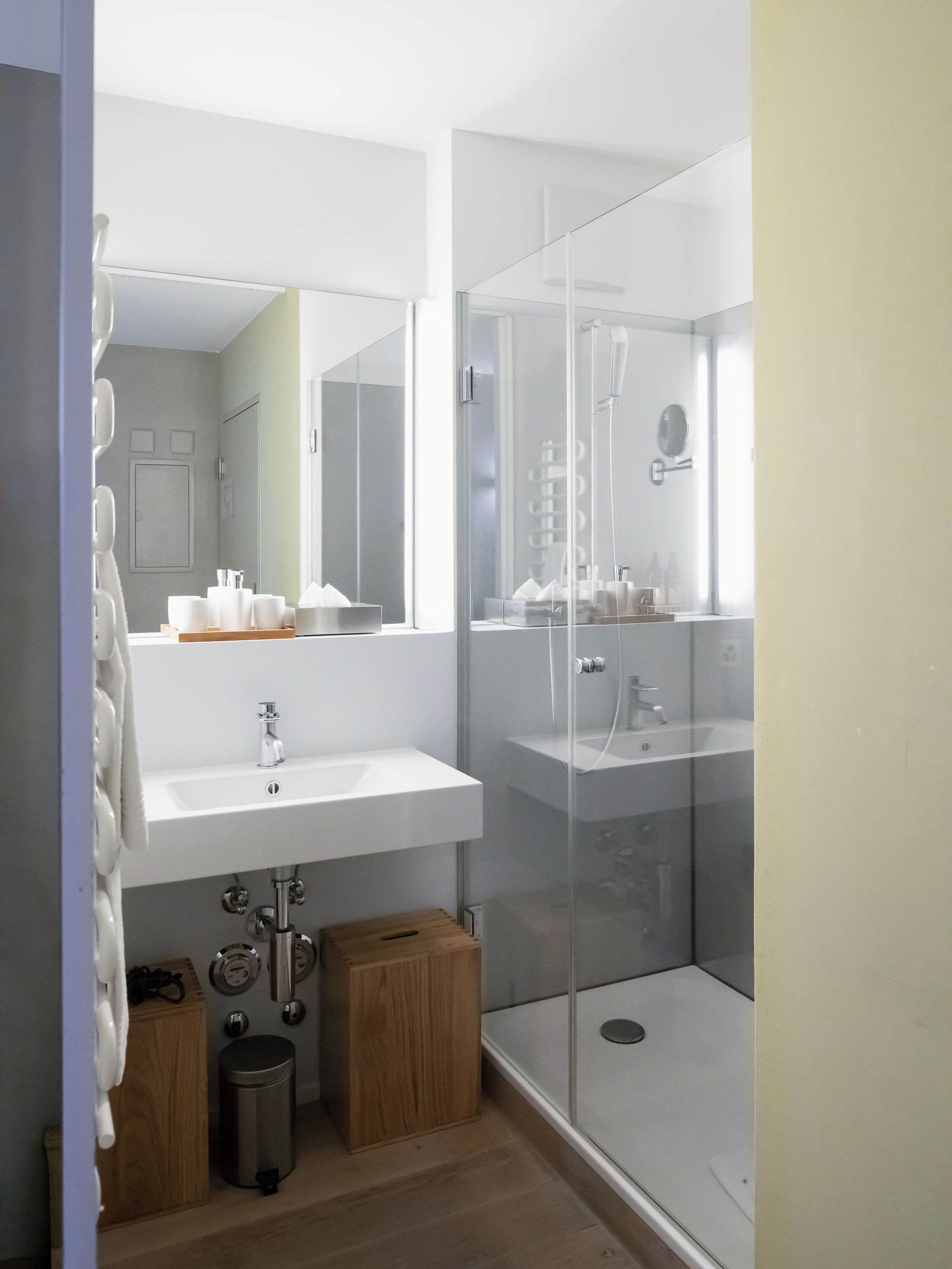 Une salle de bain moderne avec une douche à parois de verre, un lavabo blanc et un miroir au-dessus.