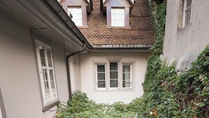 Un cortile con zona pranzo, circondato da edifici con tetti in pietra e muri ricoperti d'edera.