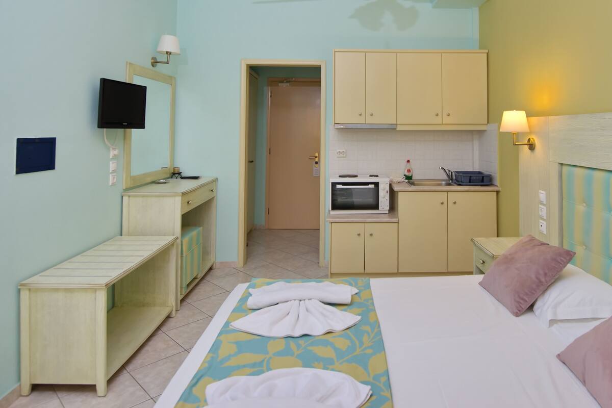 A hotel room with a bed, a desk, a television, a microwave, and a painting on the wall.