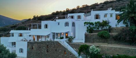 A white building with multiple levels, stone walls, and a staircase leading up to it.