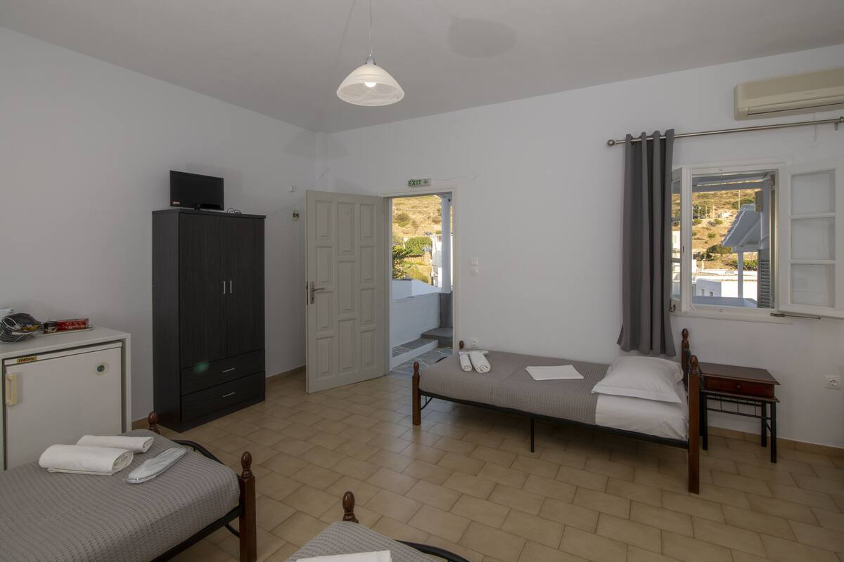 Habitación con dos camas, un armario, un escritorio y una puerta de salida.