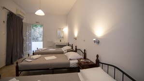 A hotel room with two beds, a bedside table with a lamp, a mirror, and an exit sign. - Prasini Gonia (Sifnos)