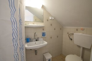 A small, clean bathroom with a sink, toilet, and a mirror above the sink. - Prasini Gonia (Sifnos)