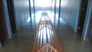 Un lungo e stretto corridoio con una scala centrale che conduce a un piano superiore.