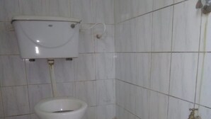 Un bagno piccolo e funzionale con il water, un serbatoio a muro e un singolo rubinetto.