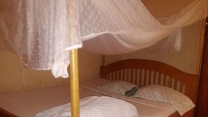 Un letto singolo con struttura in legno e tenda.