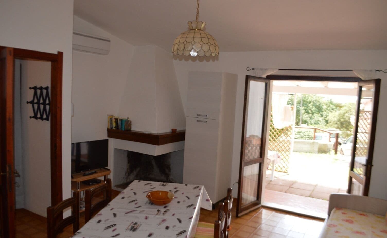 Uma sala de jantar com mesa, cadeiras, lareira e vista para o exterior.