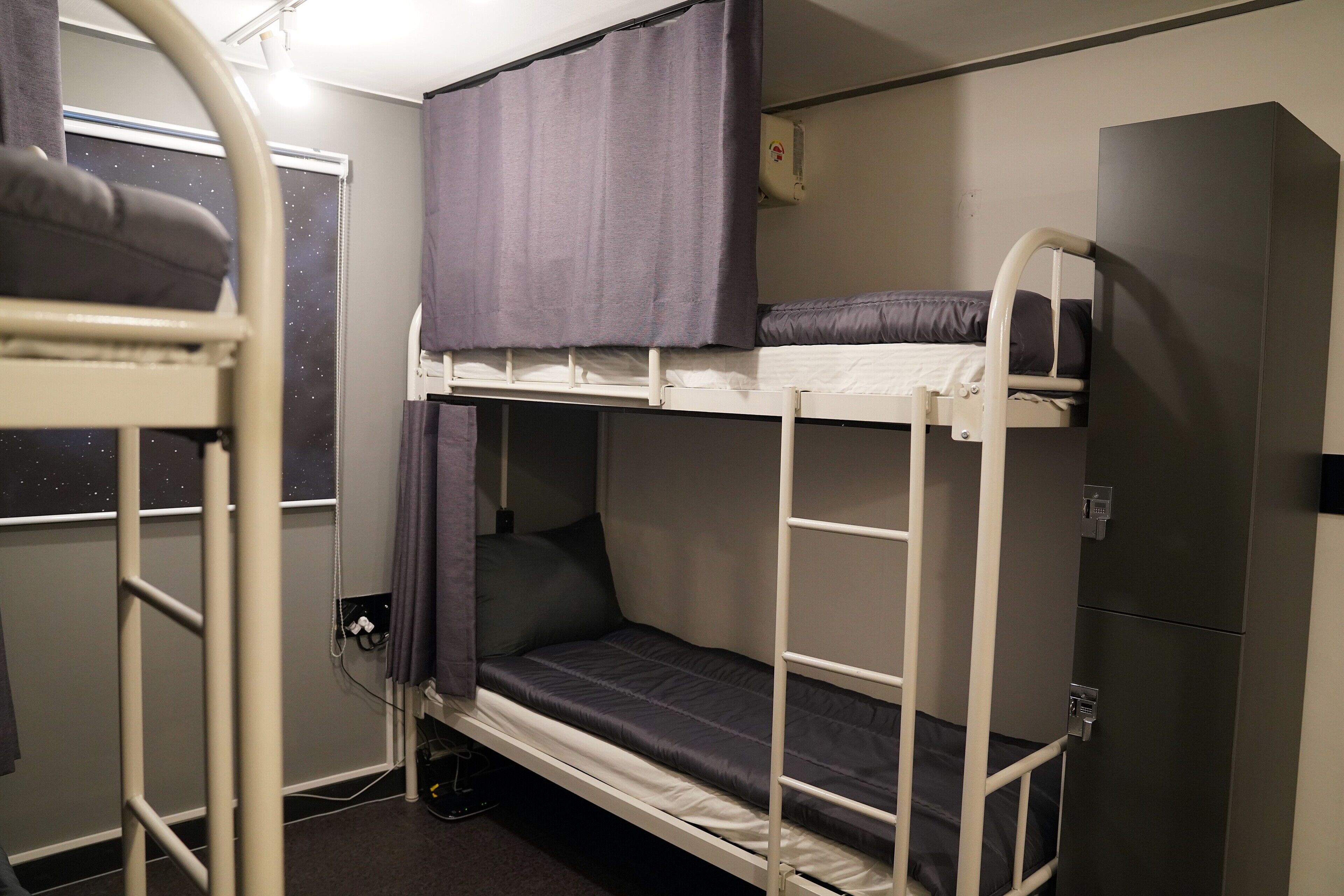 A bunk bed with a window, a curtain, and a small cabinet.