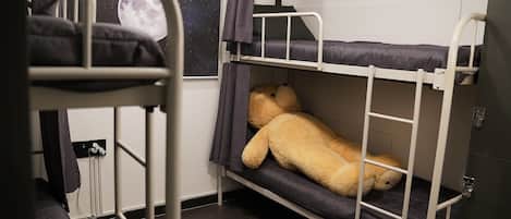 Quarto com beliche e um urso de pelúcia grande na cama de baixo.