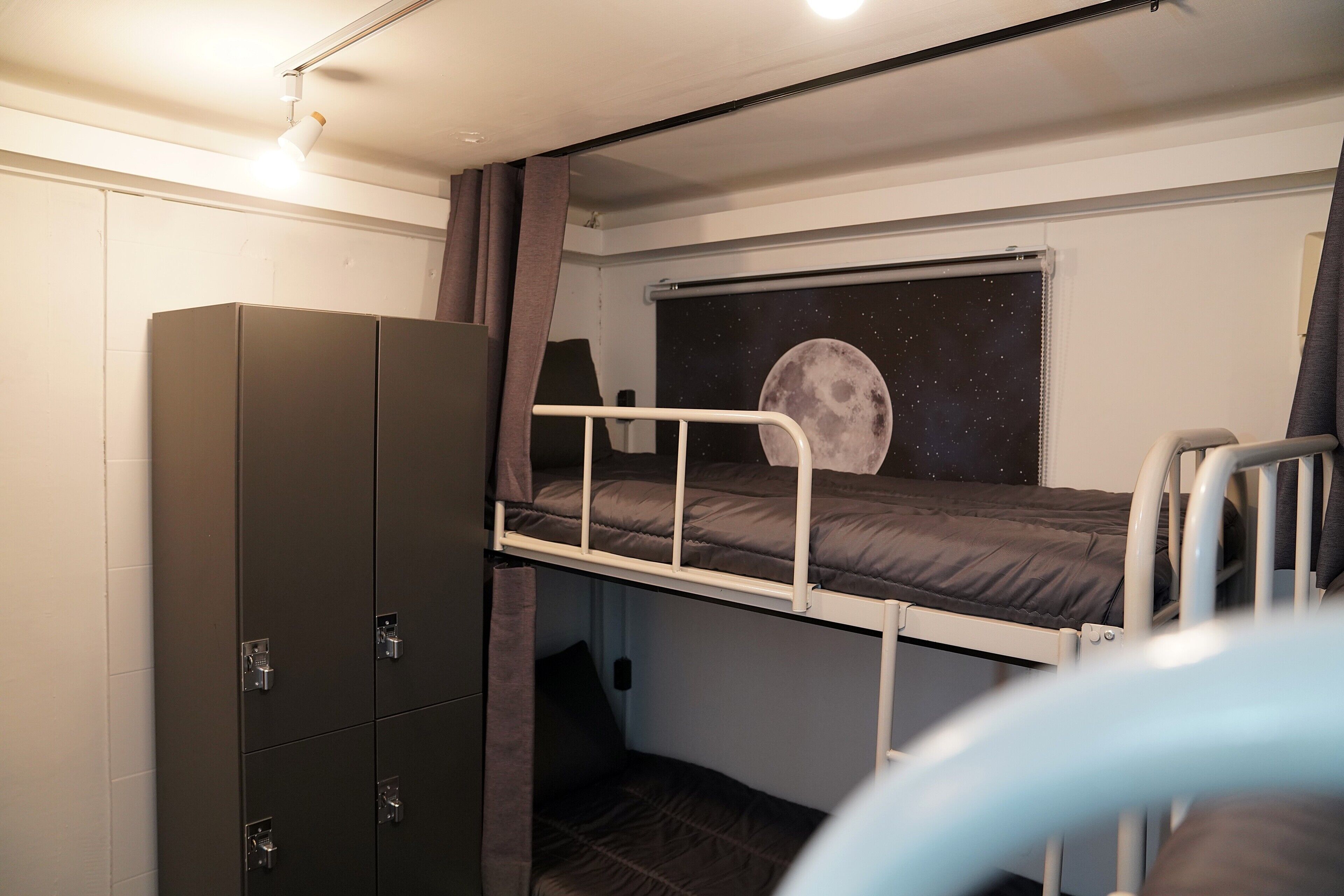 Ein Etagenbett mit Blick auf einen sternenübersäten Nachthimmel, ein Kleiderschrank und ein kleines Fenster mit Vorhängen.