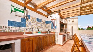 A kitchen with wooden cabinets, a tiled backsplash, and a dining area with a table and chairs. - Appartamento le Campanelle (San Felice del Benaco)