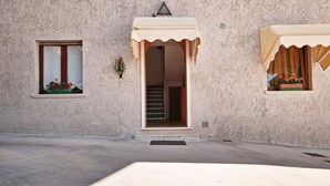 A building facade with two windows, each with a curtain and a small planter with flowers. - Appartamento le Campanelle (San Felice del Benaco)