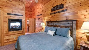Un dormitorio de cabaña de madera acogedor, con una cama grande, un televisor y un letrero que dice 'Estamos tan bendecidos'.