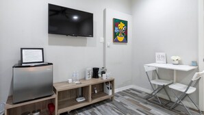 En moderne stue med et fladskærms-tv, et lille kaffehjørne og et klapbord.