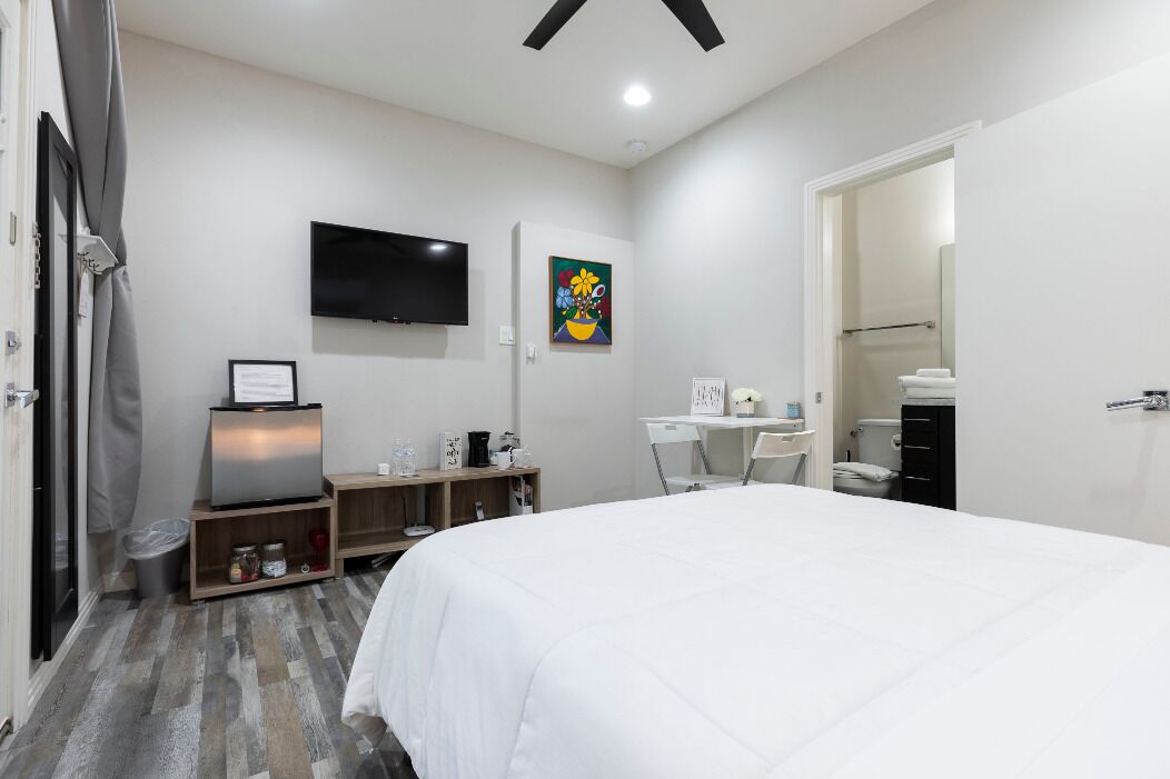 A bedroom with a bed, a TV, a desk, and a chair.