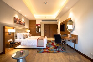 Habitación de hotel con cama, mesita de noche, escritorio, silla y espejo.