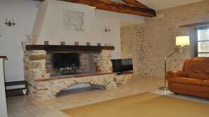 Ein Kamin aus Stein mit einem Fernseher darauf, ein braunes Ledersofa und eine Lampe.