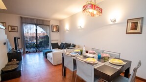 A dining area with a table set for four, a sofa, and a staircase leading to a balcony.