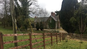 Une propriété rurale comprenant une maison en pierre, une clôture en bois et un champ d’herbe.