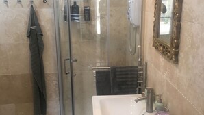 Une salle de bain moderne avec une douche à parois de verre, un lavabo blanc avec un miroir et un porte-serviettes.