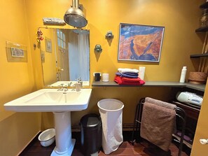 Ein Badezimmer mit Waschbecken, Spiegel, Handtuchhalter und einer gerahmten Karte an der Wand.