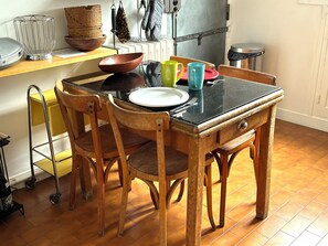 Une table à manger avec des chaises, un saladier, une assiette et quelques tasses.