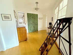 Ein geräumiger Flur mit Holzboden, einer Treppe und einer Wand mit Grüner Struktur.