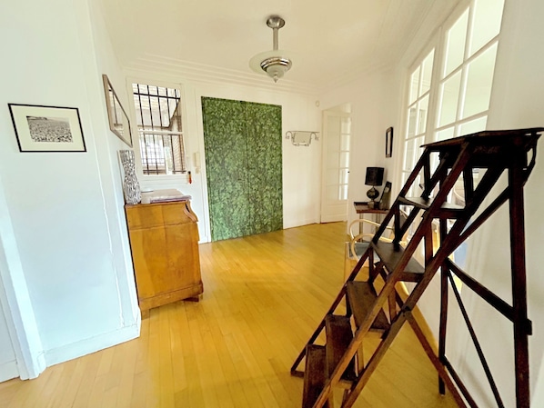Un hall d’entrée spacieux avec un plancher en bois, un escalier et un mur vert à texture.
