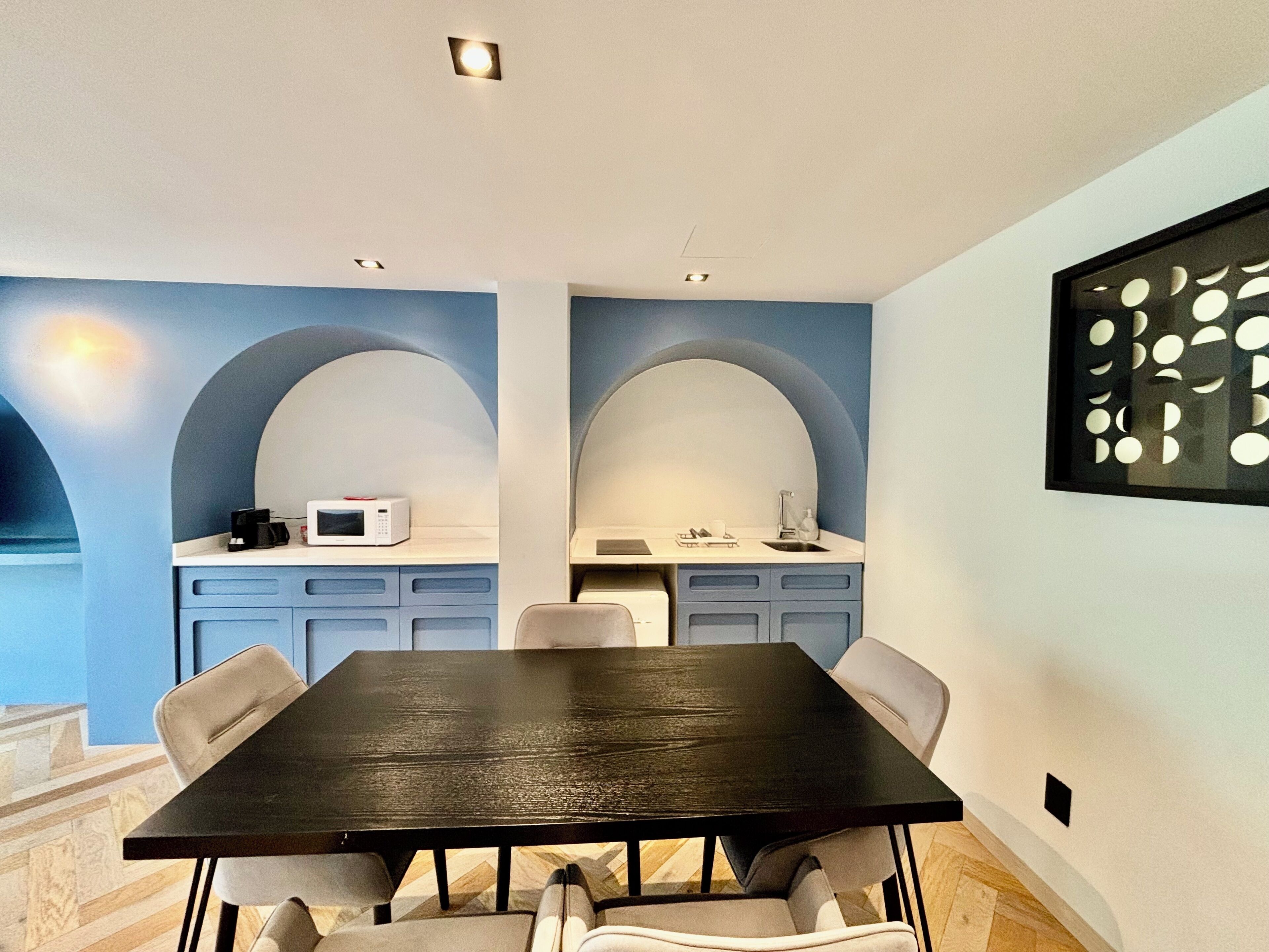 Una cocina moderna con una mesa y sillas de madera oscura, un microondas y un lavabo.