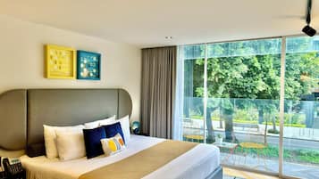 Une chambre d’hôtel moderne dotée d’un grand lit, d’un téléphone sur la table de chevet et offrant une vue sur l’espace extérieur grâce à de grandes fenêtres du sol au plafond.