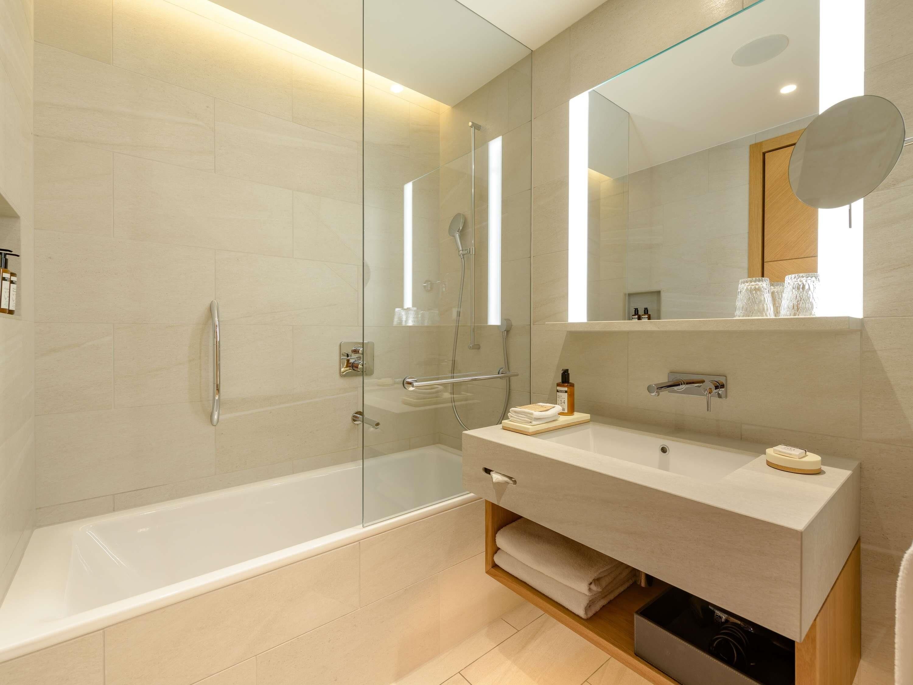 A modern bathroom with a glass-enclosed shower, a vanity with a mirror, and a bathtub.