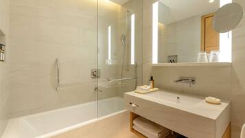 A modern bathroom with a glass-enclosed shower, a vanity with a mirror, and a bathtub.