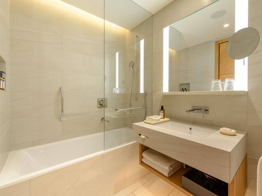 A modern bathroom with a glass-enclosed shower, a vanity with a mirror, and a bathtub.