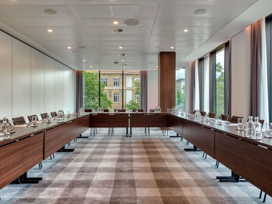 A conference room with a long table, chairs, and a checkered carpet.