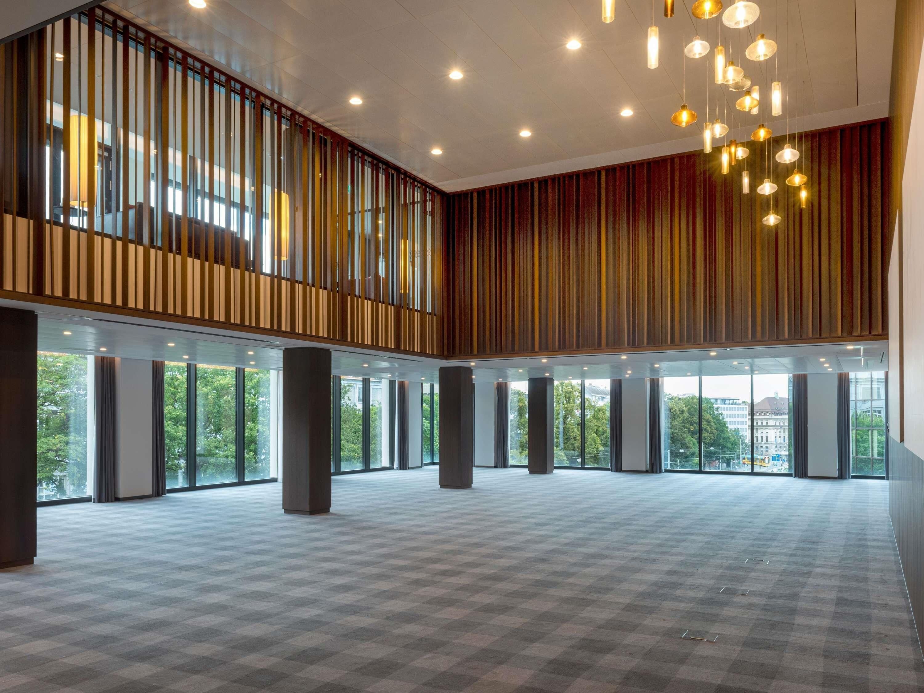 A spacious, modern interior with large windows, a high ceiling, and a checkered floor pattern.