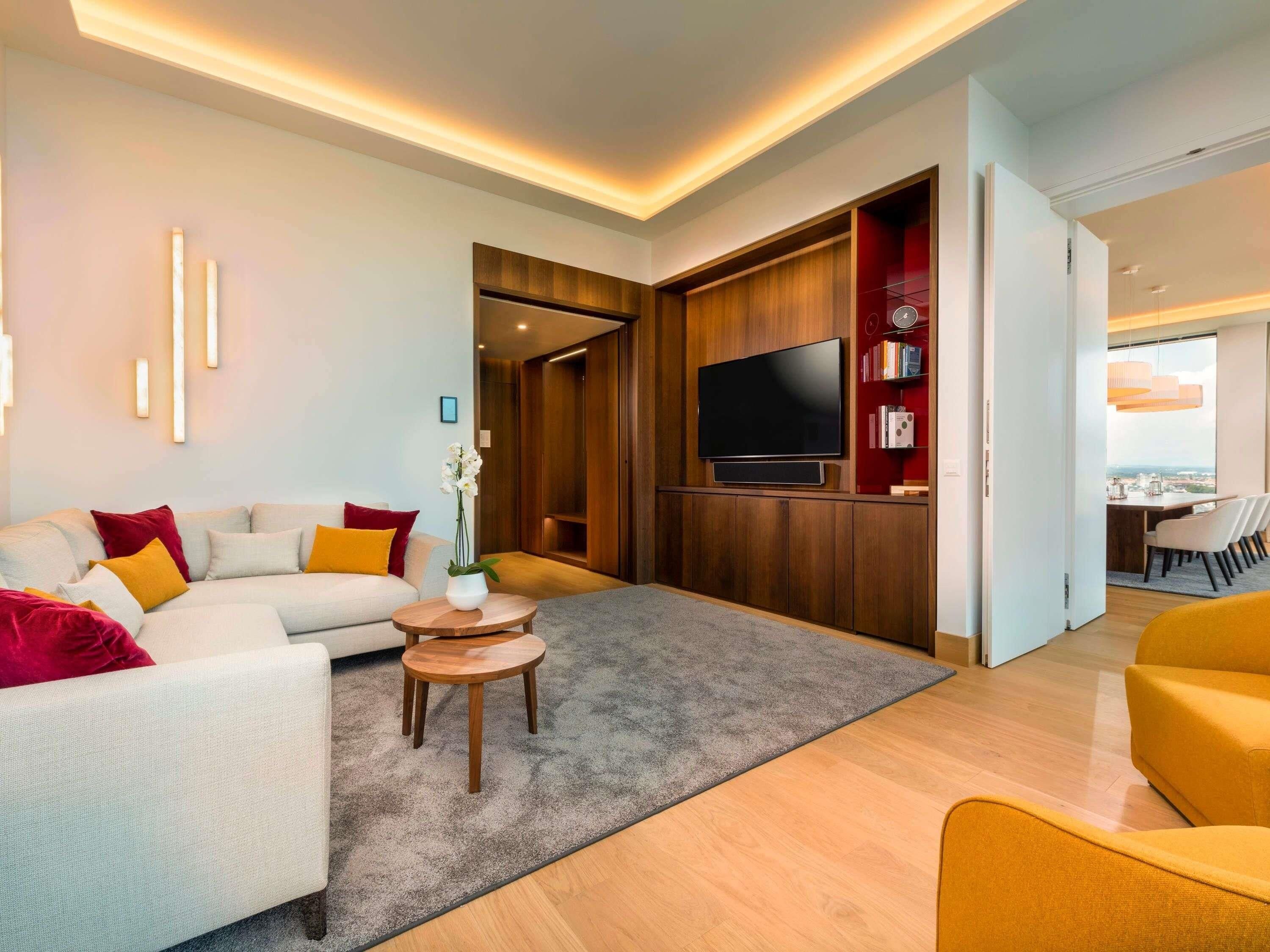 Una sala moderna con un sofá, una mesa de centro y un televisor de pantalla plana montado en una pared de madera.
