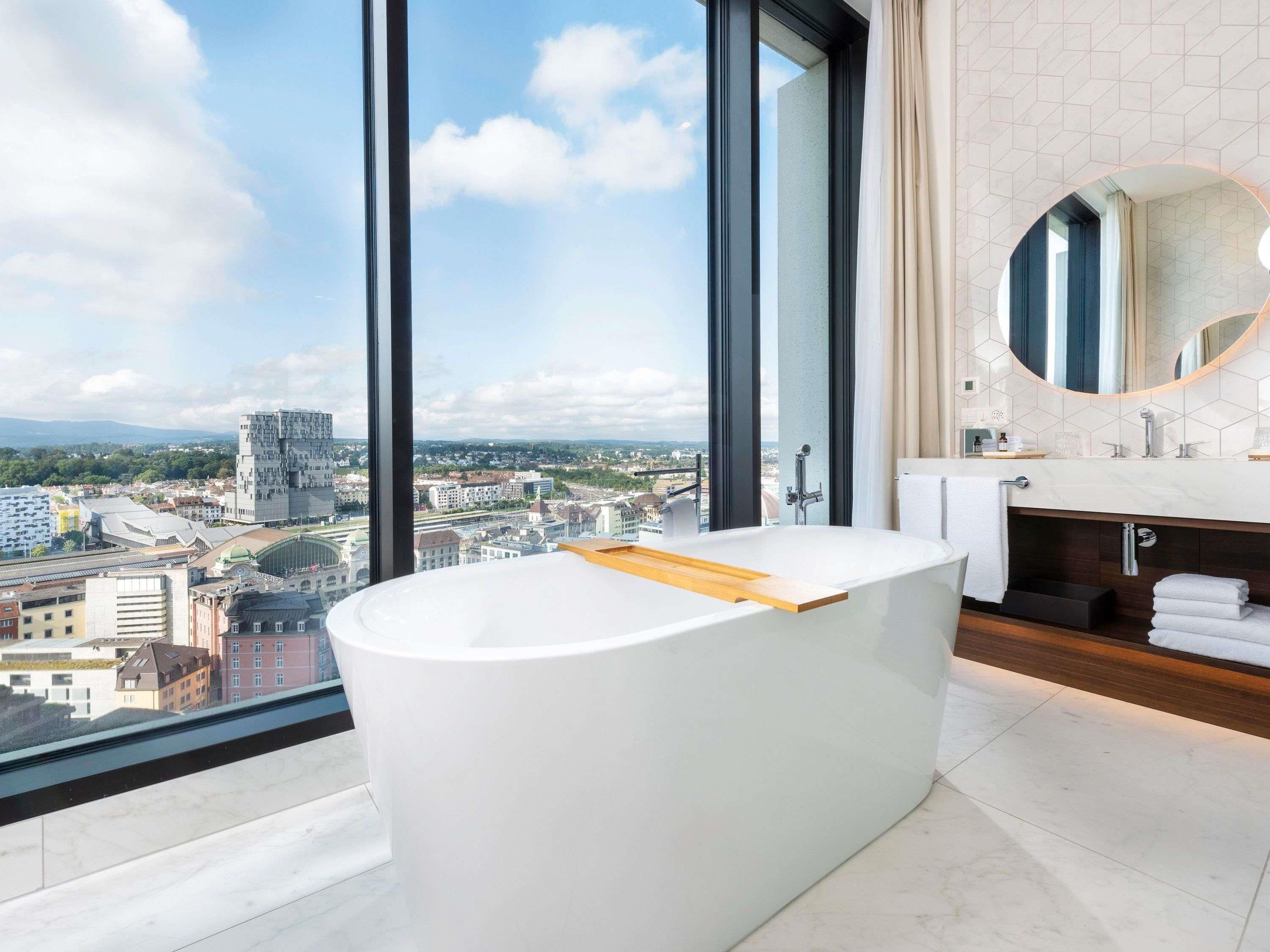 Une salle de bain moderne avec une baignoire sur pieds, un grand miroir et une vue sur la ville.