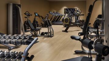 Un gimnasio con diversos equipos de ejercicio, incluyendo cintas de correr, máquinas de pesas y mancuernas.