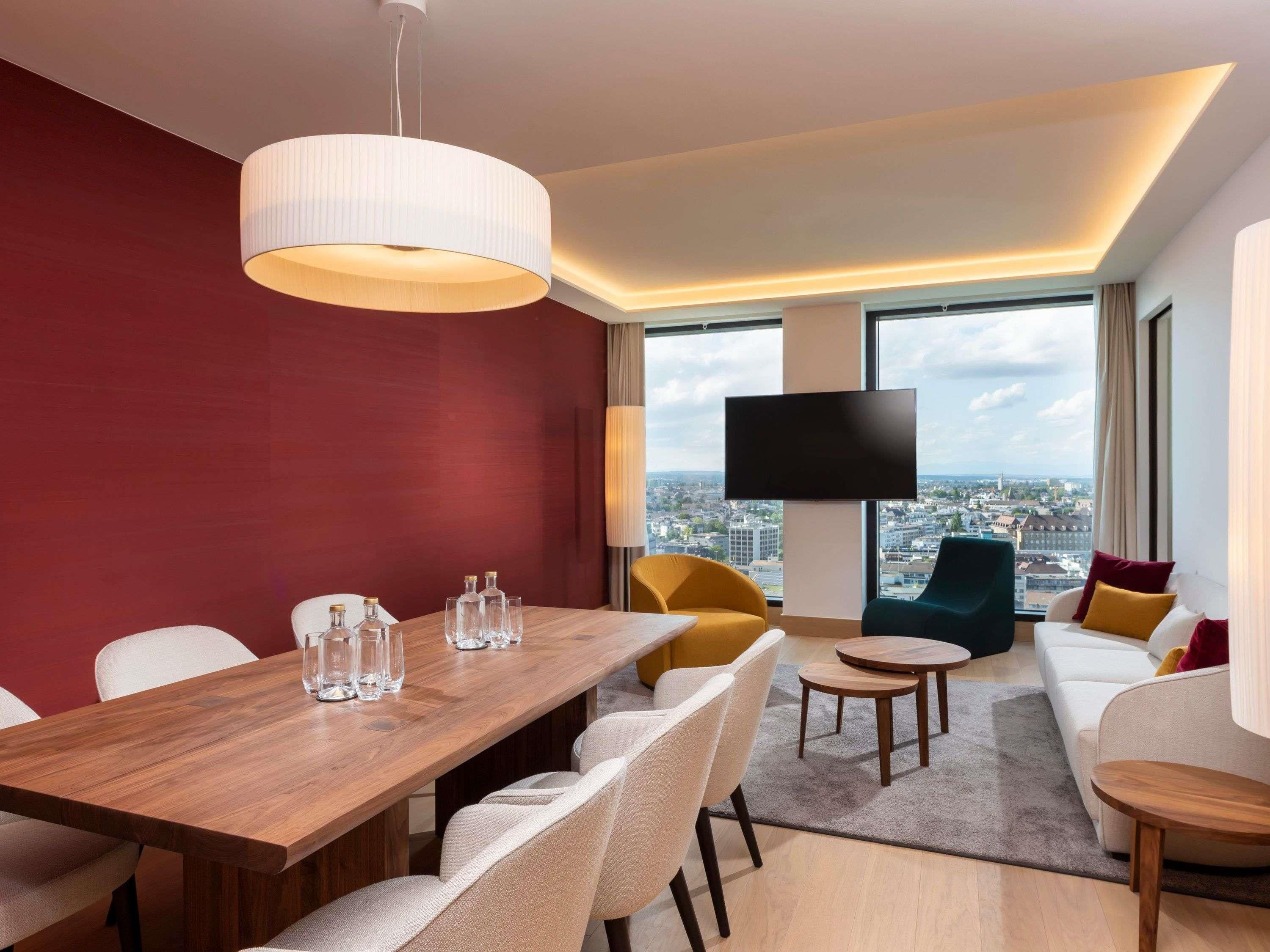 Una camera d'albergo moderna con zona pranzo, divano e televisione.