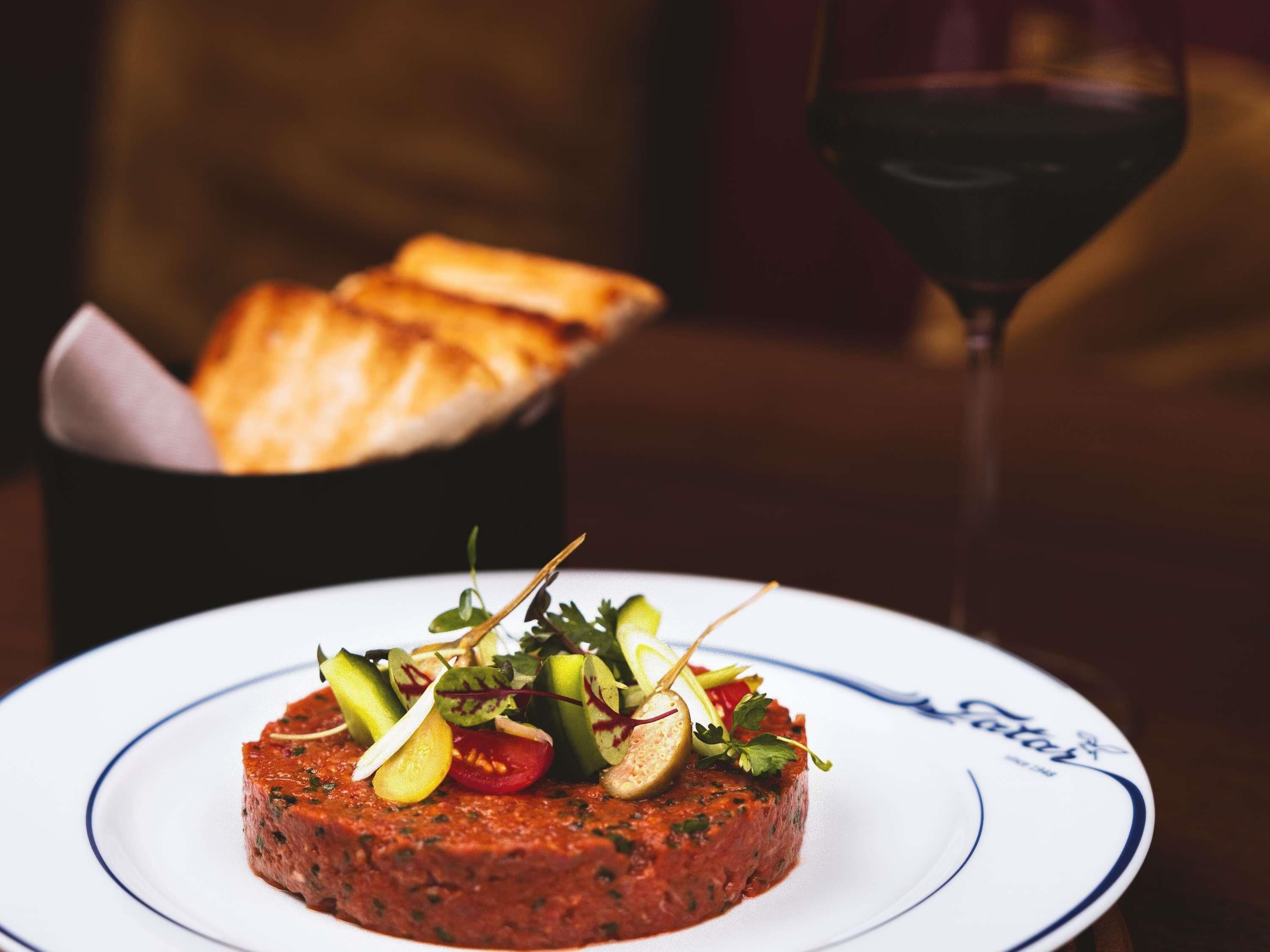 Ein Teller mit Essen, ein Glas Rotwein und ein Korb mit Brot.